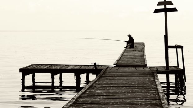 fisherman on the old bridge on the river or lake. photo. black and white