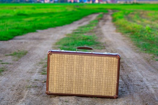 Retro styled old suitcase on a countryside road