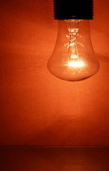 Closeup of glowing light bulb on nice red wall background