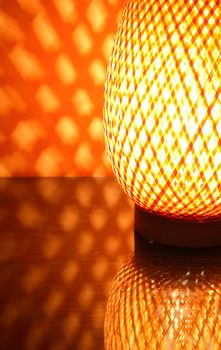 Nice wicker glowing desk lamp with reflection against red wall