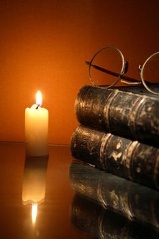 Vintage still life with lighting candle near old book