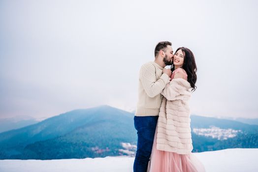 a bride in a fur coat with a fiance among the Carpathian mountains