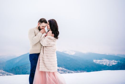 a bride in a fur coat with a fiance among the Carpathian mountains