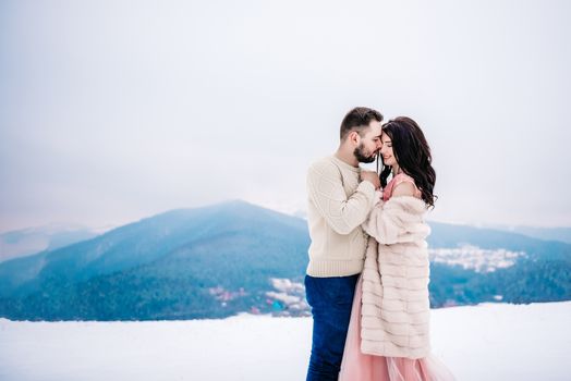 a bride in a fur coat with a fiance among the Carpathian mountains