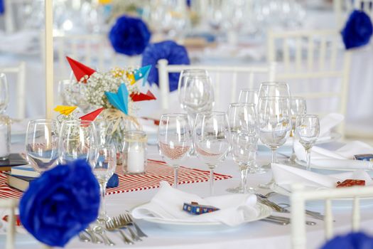 Circle dinner table served with white crockery and decorated with colorful objects.