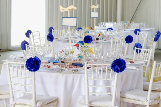 Circle dinner table served with white crockery and decorated with colorful objects.