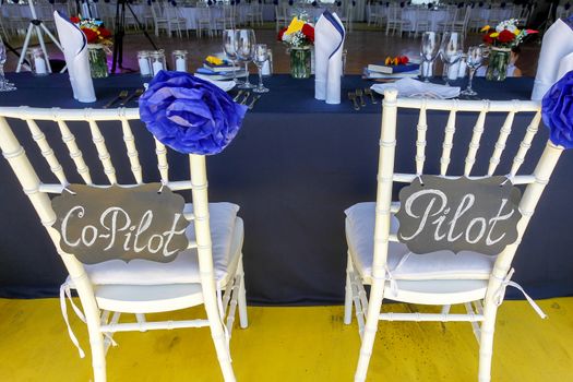 Circle dinner table served with white crockery and decorated with colorful objects.