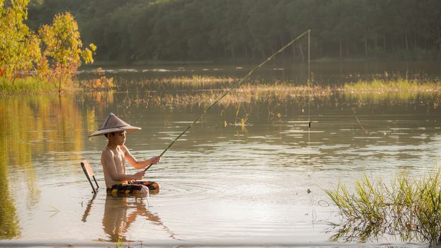 asian little boy fishing in a lake