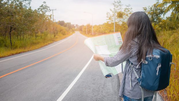 Hipster Asian woman backpacker look map on trip