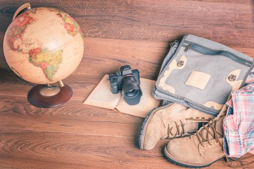 Front view of globe,camera,book,bag,boots and shirt, wooden background,vintage look for travel concept.