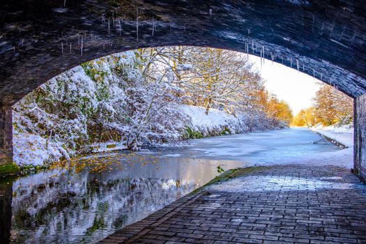 View of frozen Birmingham Canal under a bridge