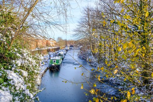 Snow covered canal boats seen in frozen Birmingham canal.