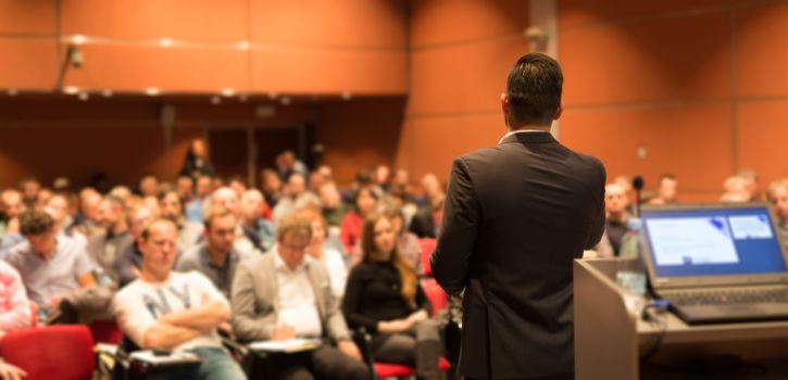 Speaker giving a talk on corporate Business Conference. Audience at the conference hall. Business and Entrepreneurship event.