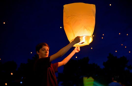 Teen boy in summer night with paper lantern