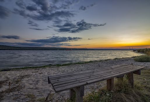 Lonely bench by the sea at sunset 