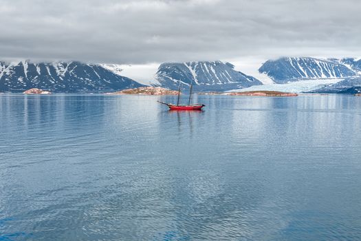 Glacier, mountains and sailing ship in a cloudy day in Svalbard islands, Norway