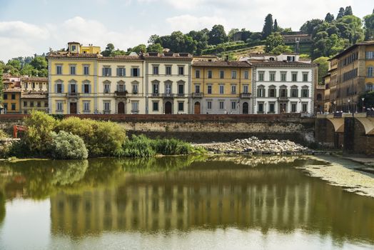 Scenic view of the Lungarno at historic center of Florence, Italy. Facades of old medieval houses on waterfront of the Arno River. Florence is a popular tourist destination of Europe.