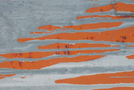 fragment of an iron surface is covered with orange and grey color paint, which has long been under the influence of different climatic conditions