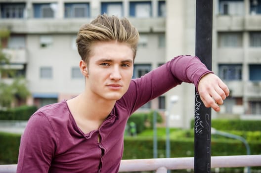 Handsome blond young man outdoors, looking away to a side