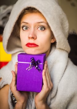 young caucasian woman is holding a gift in her hands. woman celebrating holiday with present