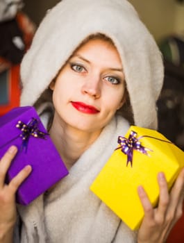 young caucasian woman is holding two gifts in her hands. woman celebrating holiday with presents