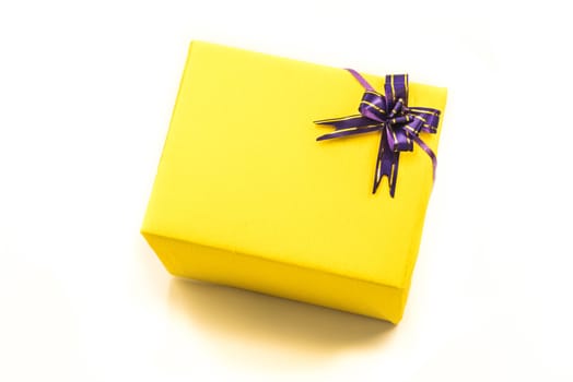 bright yellow hand made gift box with nice crepe wrapping and purple bow. Happy holidays.