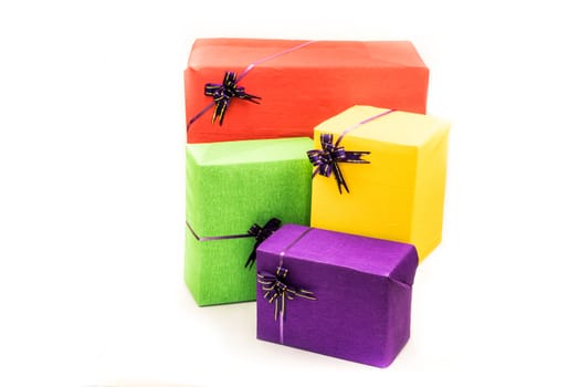 pile of colorful gift boxes wrapped in crepe paper with purple bows. Holiday presents concept