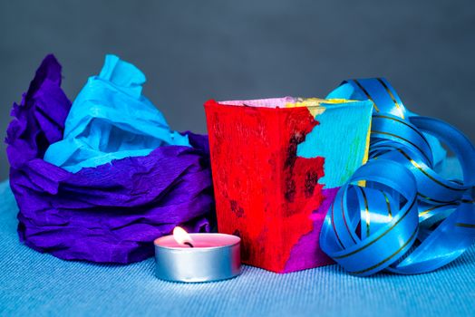 christmas craft composition on the blue tablecloth. candle with fir tree branch, crepe paper and blue tablecloth