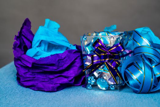 christmas craft composition on the blue tablecloth. candle with gems and blue ribbon