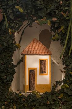 Curious ceramic tiny house in Portuguese style in a garden.