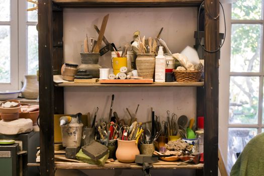 Artist studio shelf with used painting tools and brushes.