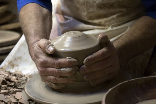 Close up view of the hands of ceramic artist making a piece from clay.