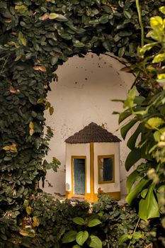 Curious ceramic tiny house in Portuguese style in a garden.