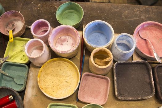 Artist table with used painting buckets and brushes.