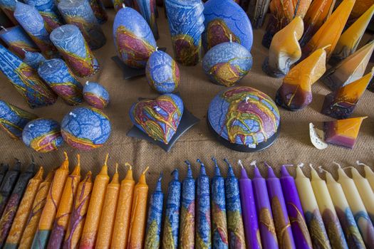 View of several handmade candles in tones of blue, yellow and other colors.