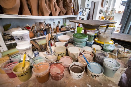 Artist studio with used painting buckets and brushes.