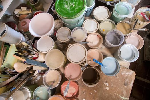 Artist studio with used painting buckets and brushes.