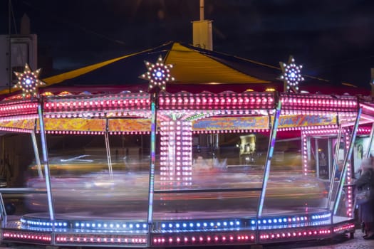 Colorful spinning carousel lights in amusement park.
