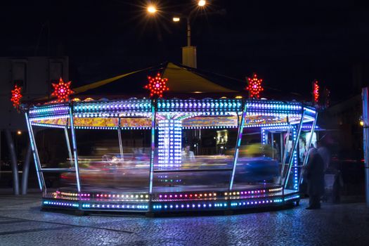 Colorful spinning carousel lights in amusement park.