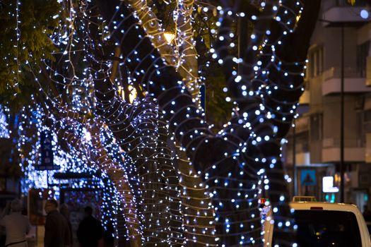 Beautiful view of christmas themed wrapped trees with decorative lights in Olhao city, Portugal.