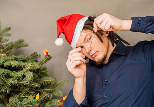 young european man in christmas hat with a hand made star decoration with a fir tree in background