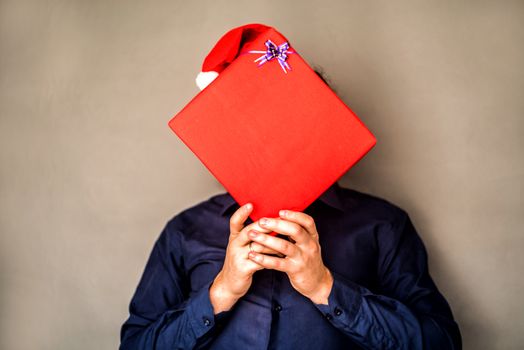 guy in santa hat holding a gift covering his face