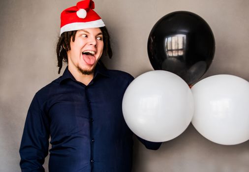 smiling young caucasian man with afro hair holding balloons. christmas concept