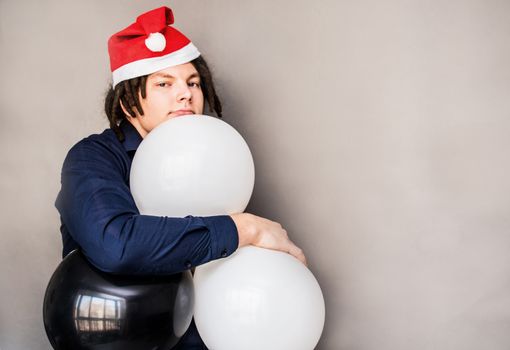 smiling young caucasian man with afro hair hugging balloons. christmas concept
