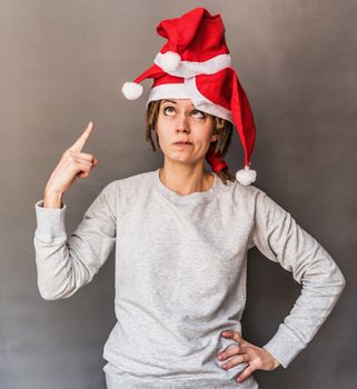 funny young caucasian woman with tree christmas hats pointing her finger at hats