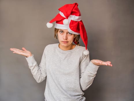 emotions. christmas concept. caucasian woman in santa hats shrugging her shoulders in surprise