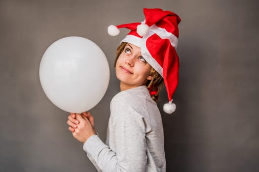 christmas concept. young caucasian woman with tree santa hats holding a balloon dreaming and smiling
