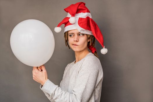 christmas concept. young caucasian woman with funny face in tree santa hats holding a balloon