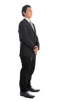 Full body side view of handsome young Southeast Asian businessman standing isolated on white background. 