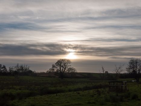 surreal sky clouds sun set sun field meadow trees grass land; essex; england; uk